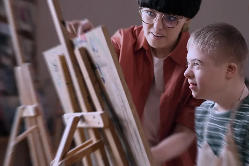 insegnante che aiuta bambino con disabilità a dipingere