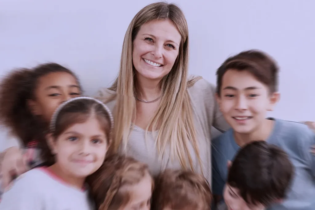 docente che abbraccia bambini tutti felici