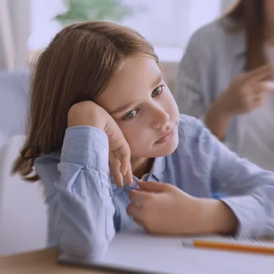 Bambina seduta al banco, in difficoltà a mantenere l’attenzione durante un’attività di classe