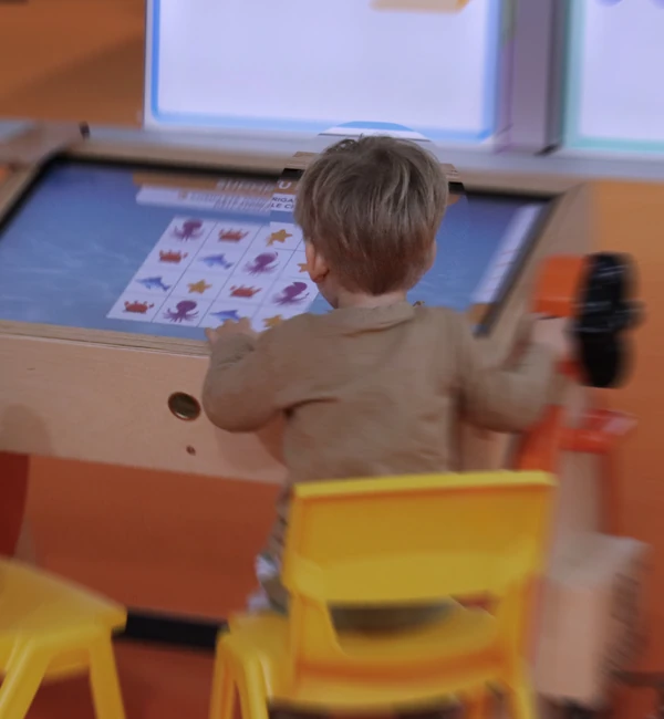 Bambino e insegnante al banco interattivo Pinguin durante un’attività digitale guidata