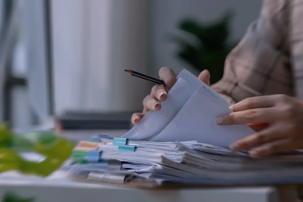 Mani che organizzano documenti e appunti di studio su una scrivania durante un percorso formativo