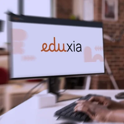 Persona che utilizza la piattaforma digitale Eduxia su monitor desktop per attività di formazione online