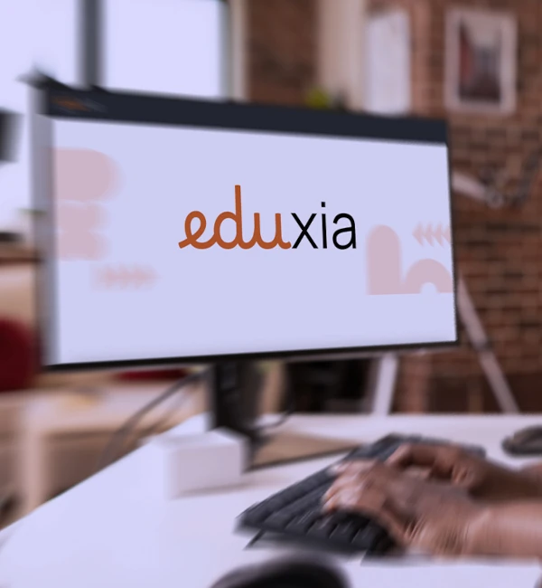 Persona che utilizza la piattaforma digitale Eduxia su monitor desktop per attività di formazione online